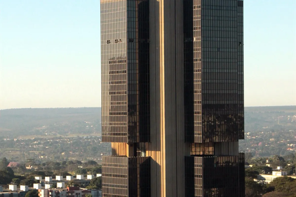 Fachada da sede do Banco Central do Brasil, torre alta de concreto e vidro escuro, em Brasília, sob céu azul