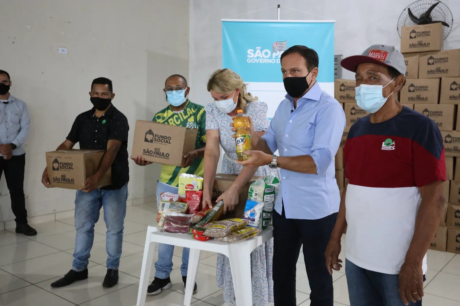Pessoas organizam caixas e alimentos de cestas básicas sobre uma mesa em Parelheiros
