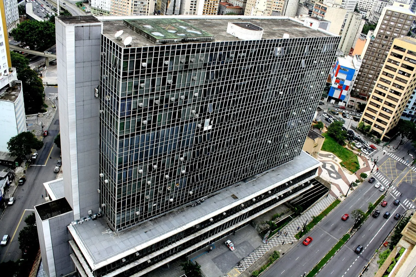 Vista aérea de um prédio modernista de vidro e concreto, com dez andares, cercado de avenidas e edifícios no centro de São Paulo