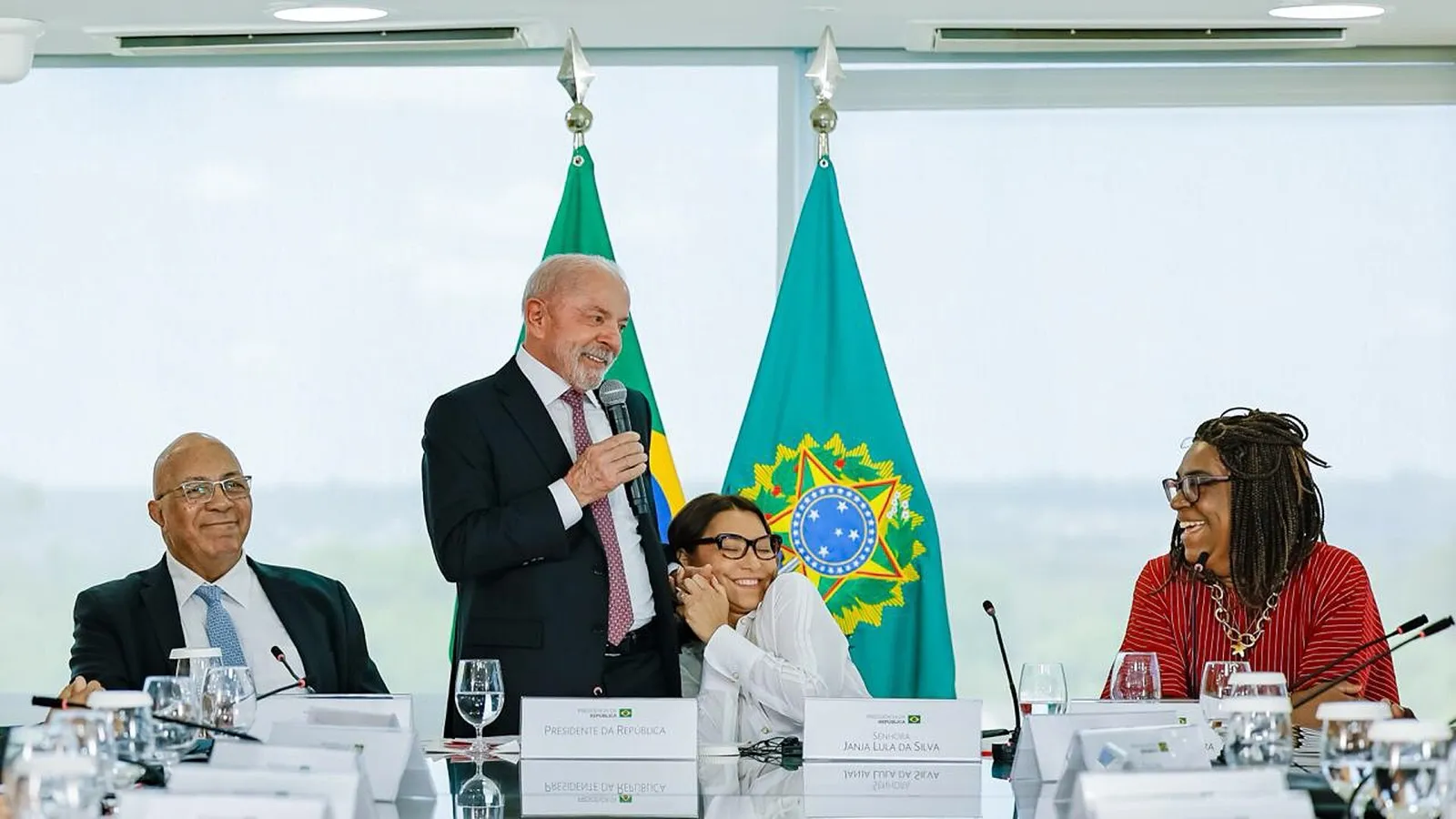 Lula fala ao microfone em mesa do Palácio do Planalto, com bandeiras do Brasil e da Presidência ao fundo