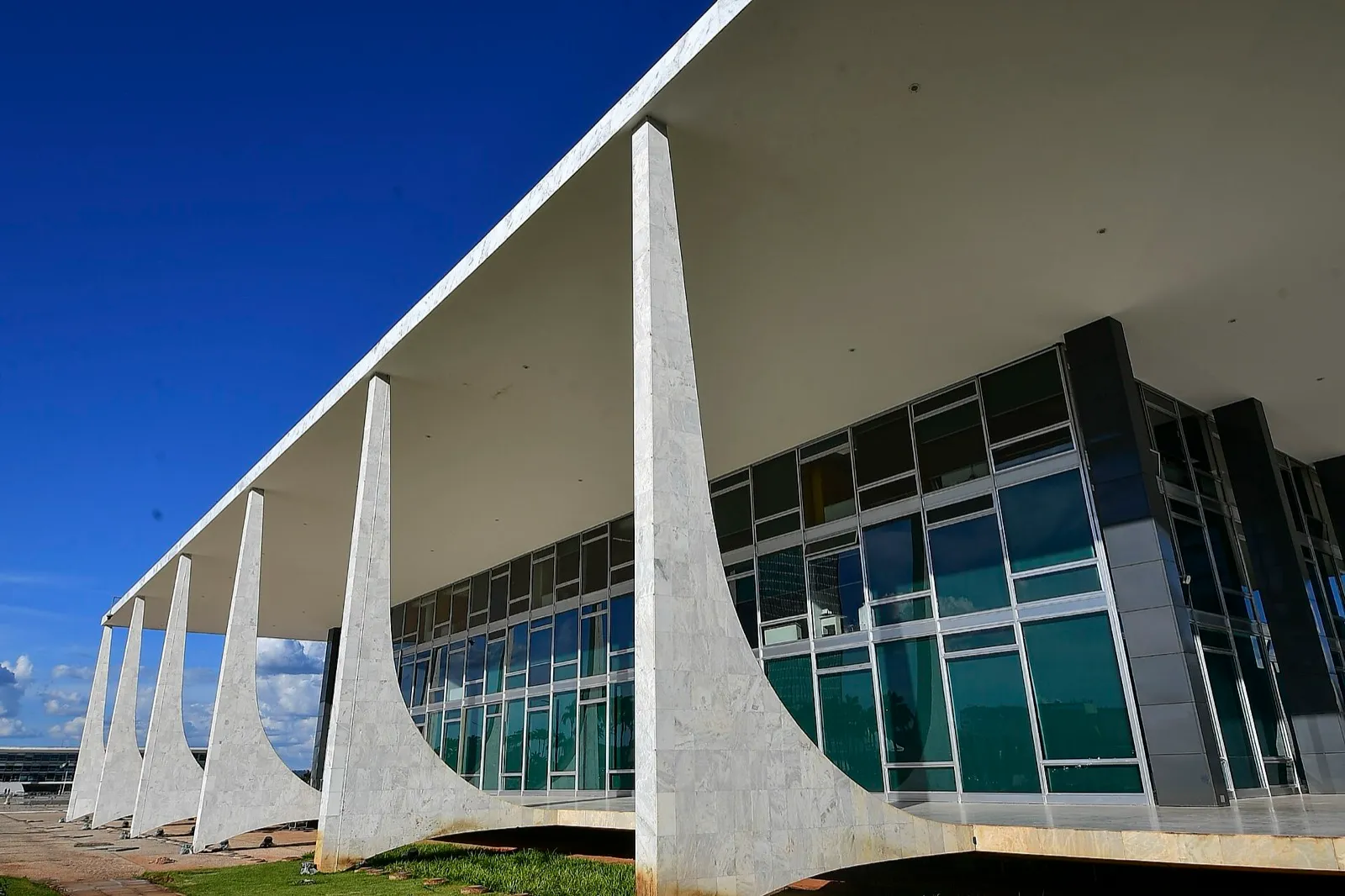 Fachada do prédio do Supremo Tribunal Federal, em Brasília, com colunas de mármore e grandes vidros sob céu azul